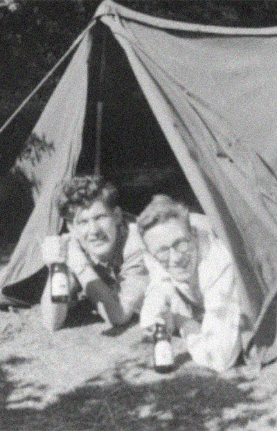 vintage black and white photo of two people under a tent holding beer bottles