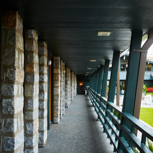 corridor with rooms to the left and balustrade separating corridor from outside seating area